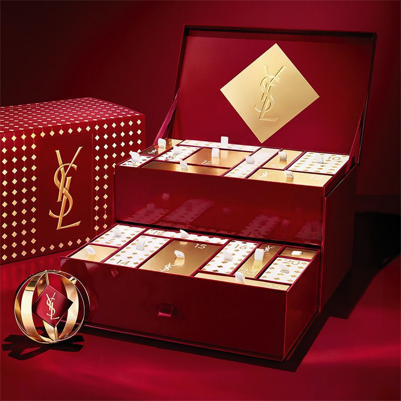 Calendario dell’Avvento beauty YSL con cosmetici e profumi in un’esposizione rossa e dorata.