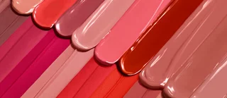 Una serie di smalti per unghie in tonalita di rosa e nude, disposti in modo ordinato.