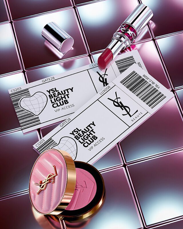 Rossetto Loveshine color Make Me Blush e due biglietti VIP per lo YSL Beauty Light Club su uno sfondo di piastrelle riflettenti.