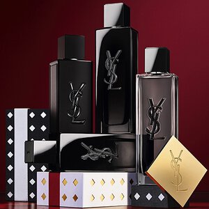 Cofanetti regalo della collezione natalizia Yves Saint Laurent e prodotti di bellezza di lusso su sfondo rosso festivo.