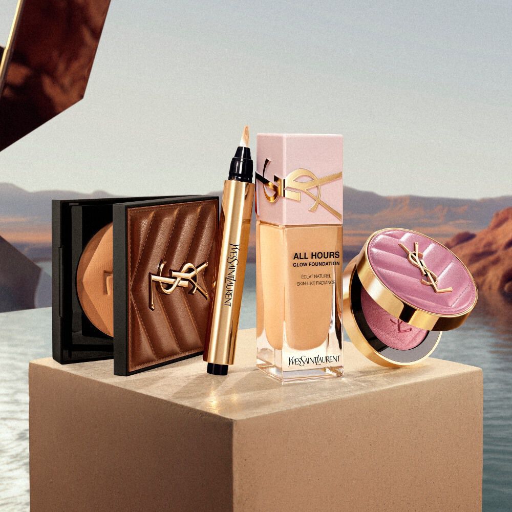 Essenziali make-up YSL esposti su un piedistallo in un’ambientazione ispirata al deserto.