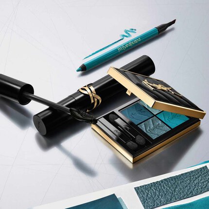 Collezione make-up di lusso YSL: palette di ombretti blu, mascara ed eye-liner su sfondo argento.