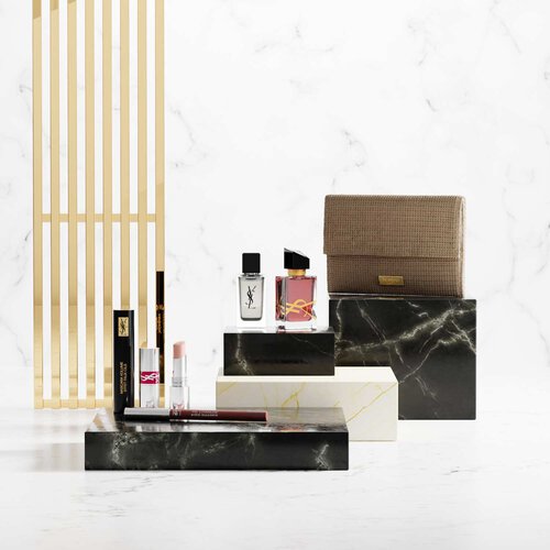 Prodotti di bellezza YSL su piedistalli di marmo di lusso.
