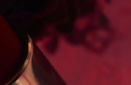 A close-up of a YSL lipstick in a striking red shade, with a blurred background that enhances its vibrant color.