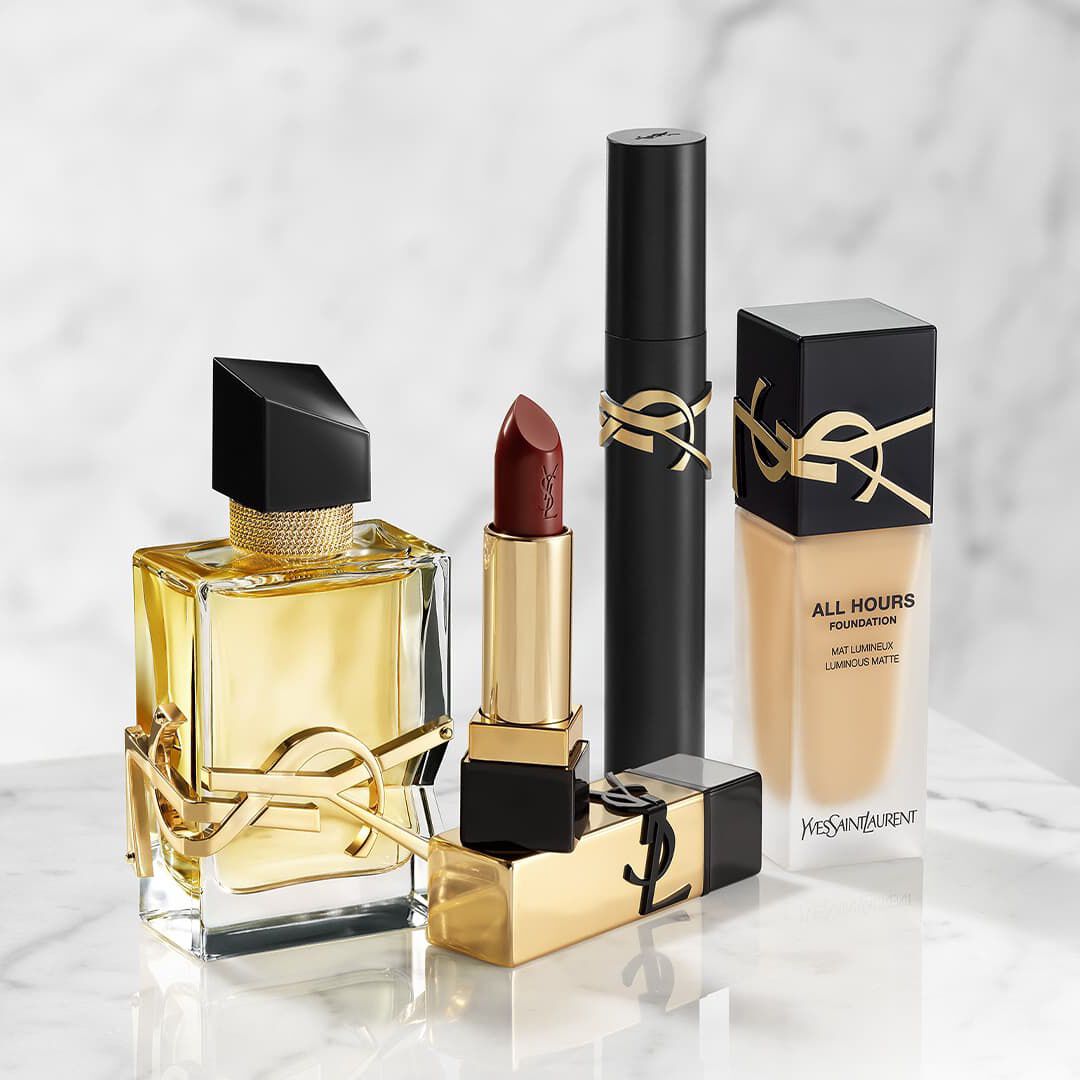 Prodotti di bellezza YSL: profumo, rossetto, mascara e fondotinta su marmo.