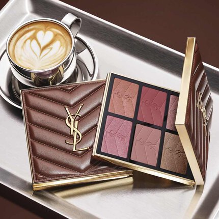 Palette trucco YSL e pochette matelasse accanto a un caffe su un vassoio argentato.