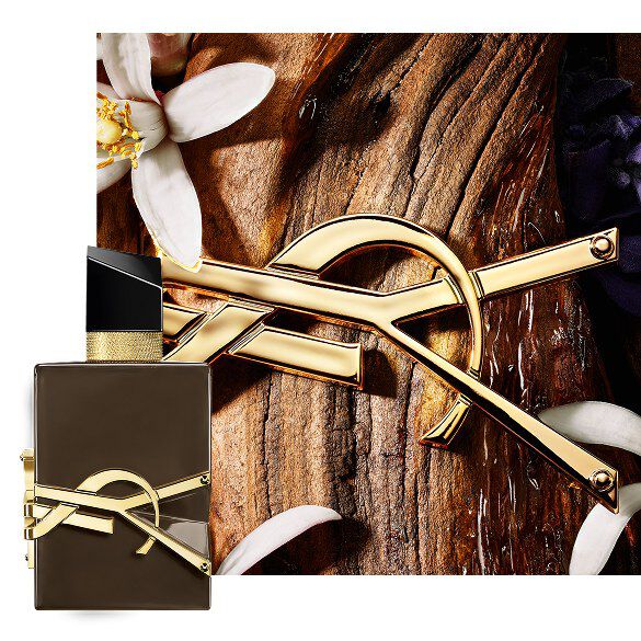 Libre Santal Couture. Flacone marrone smaltato su corteccia di sandalo, con Cassandre dorata e fiori bianchi.