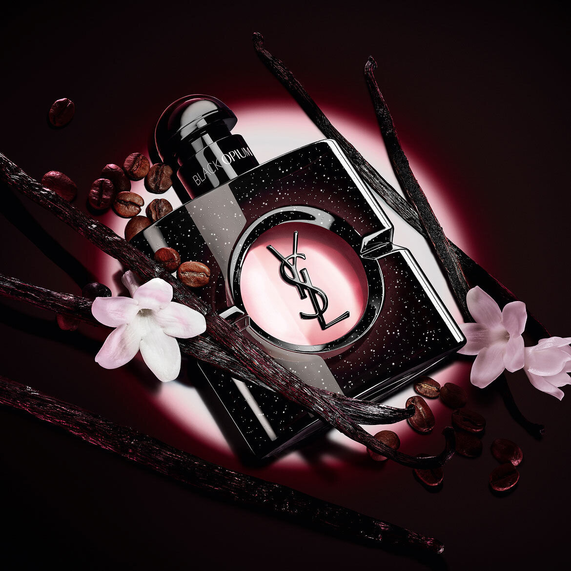 Flacone di Black Opium Eau de Parfum con fiori di gelsomino bianco, baccelli di vaniglia e chicchi di caffe tostati.