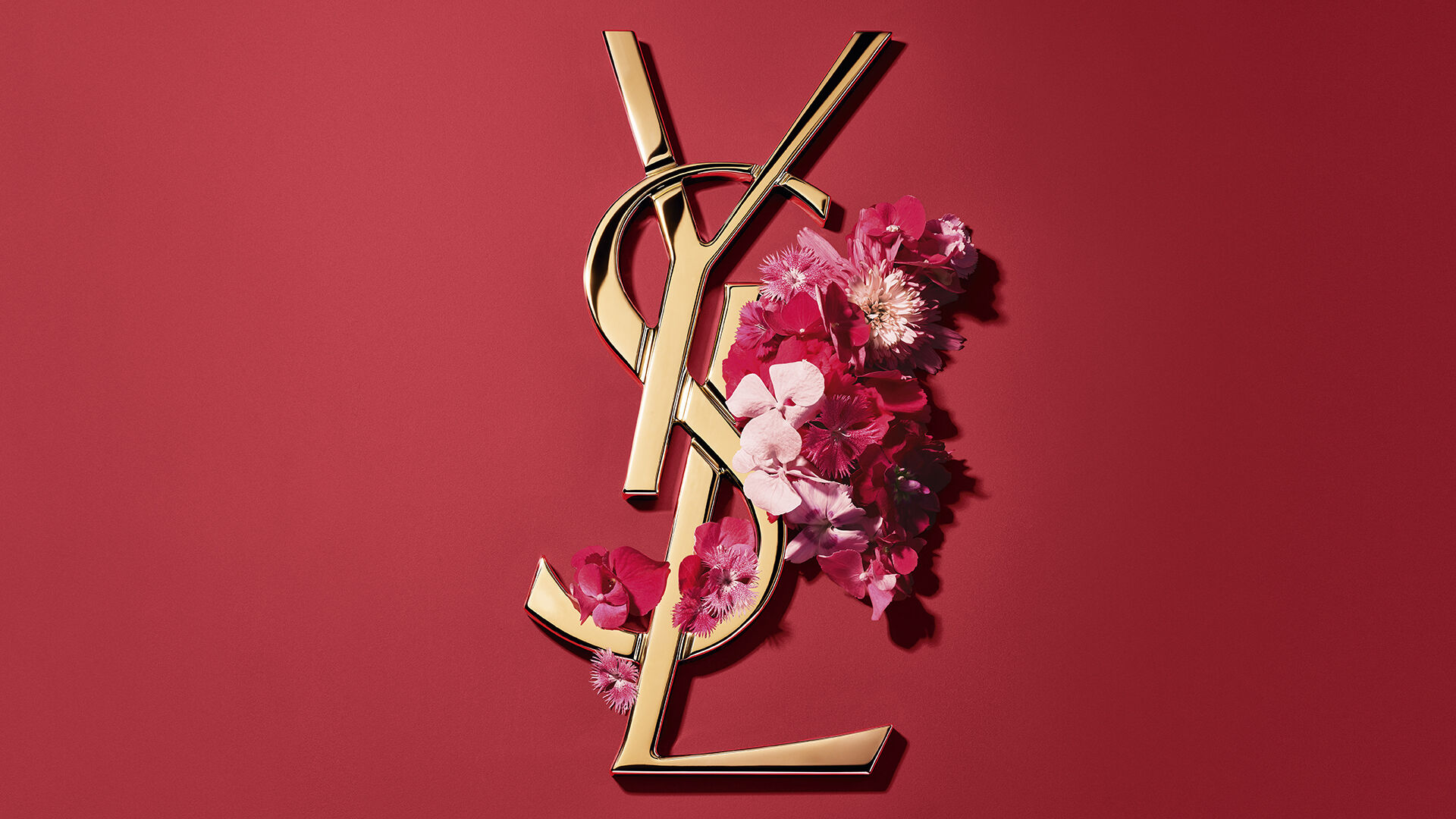 Confezione regalo YSL rossa con fiori rosa su sfondo rosso.