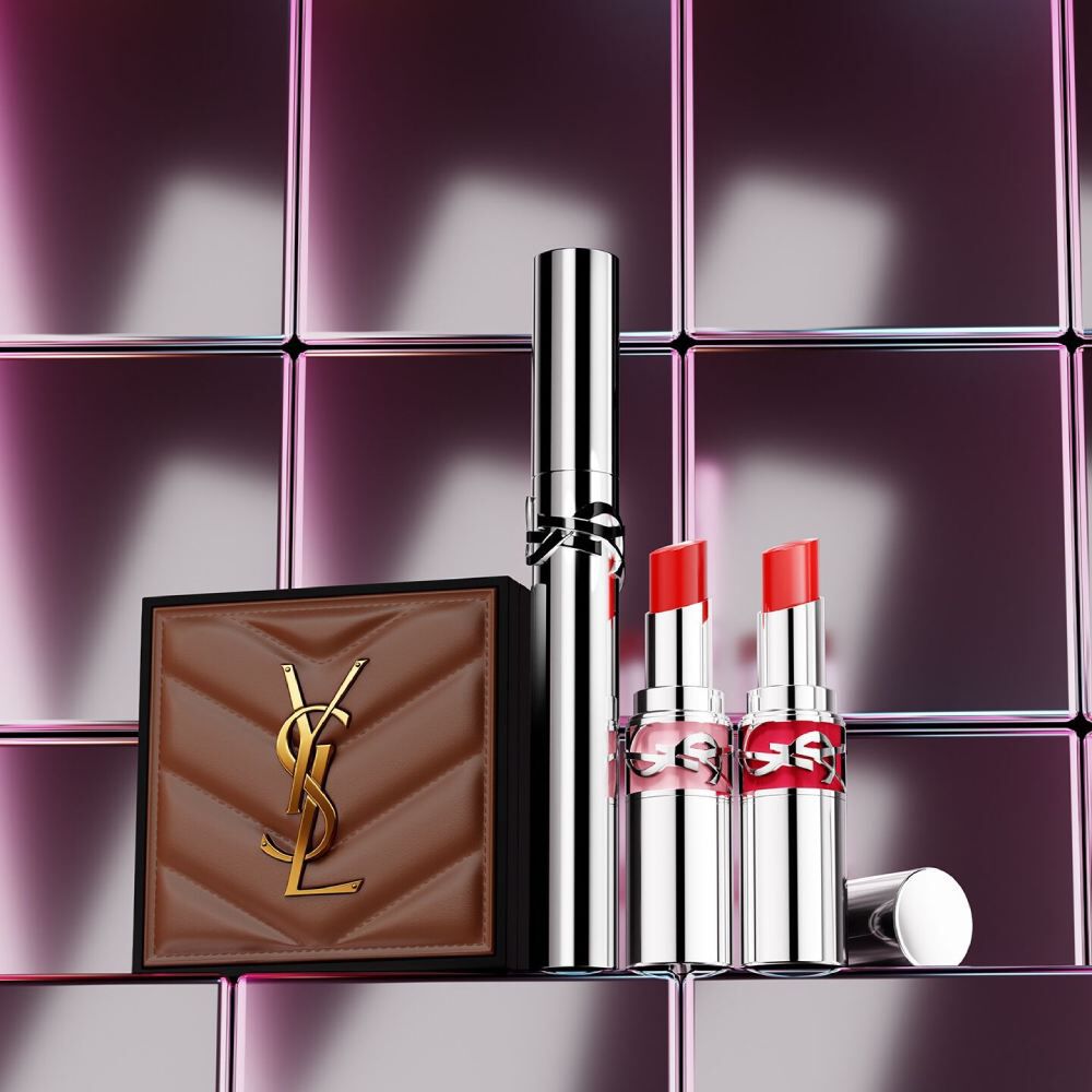  Prodotti di bellezza YSL tra cui una trousse trapuntata, un mascara e due rossetti su sfondo in piastrelle rosa lucide.