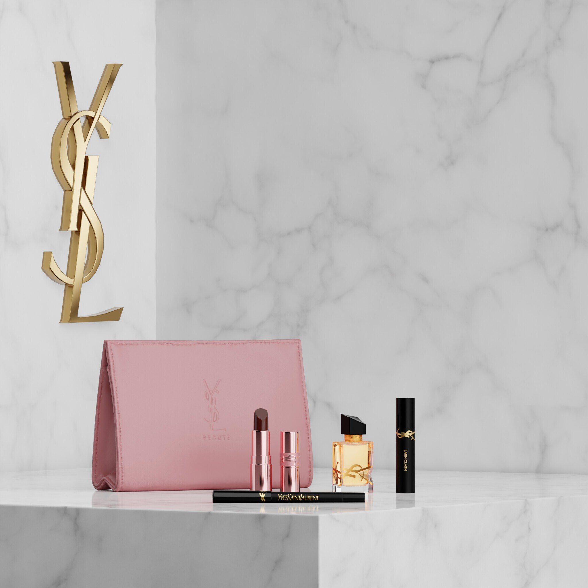 Set YSL Beauty con pochette rosa, rossetto, eyeliner, mascara e mini profumo su mensola in marmo.
