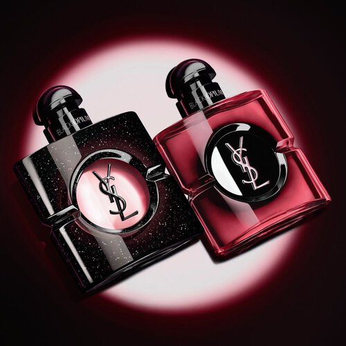 Due flaconi di profumo Black Opium di Yves Saint Laurent illuminati su sfondo scuro.