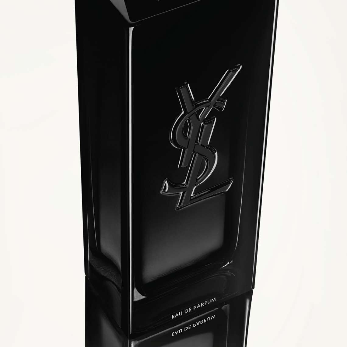 A sleek black bottle of YSL Eau de Parfum, featuring the brand's logo embossed on the front, reflecting on a glossy surface.