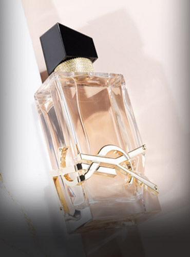 A stylish glass perfume bottle with a golden accent and a black cap, positioned elegantly against a soft, neutral background.