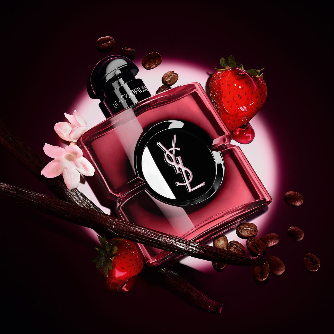 Flacone Black Opium Eau de Parfum Pink Glaze circondato da fragole fresche, baccelli di vaniglia, chicchi di caffe e gelsomino.