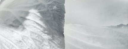 Close-up of a textured, light-colored surface with smooth and rippled patterns, creating an abstract, icy appearance.