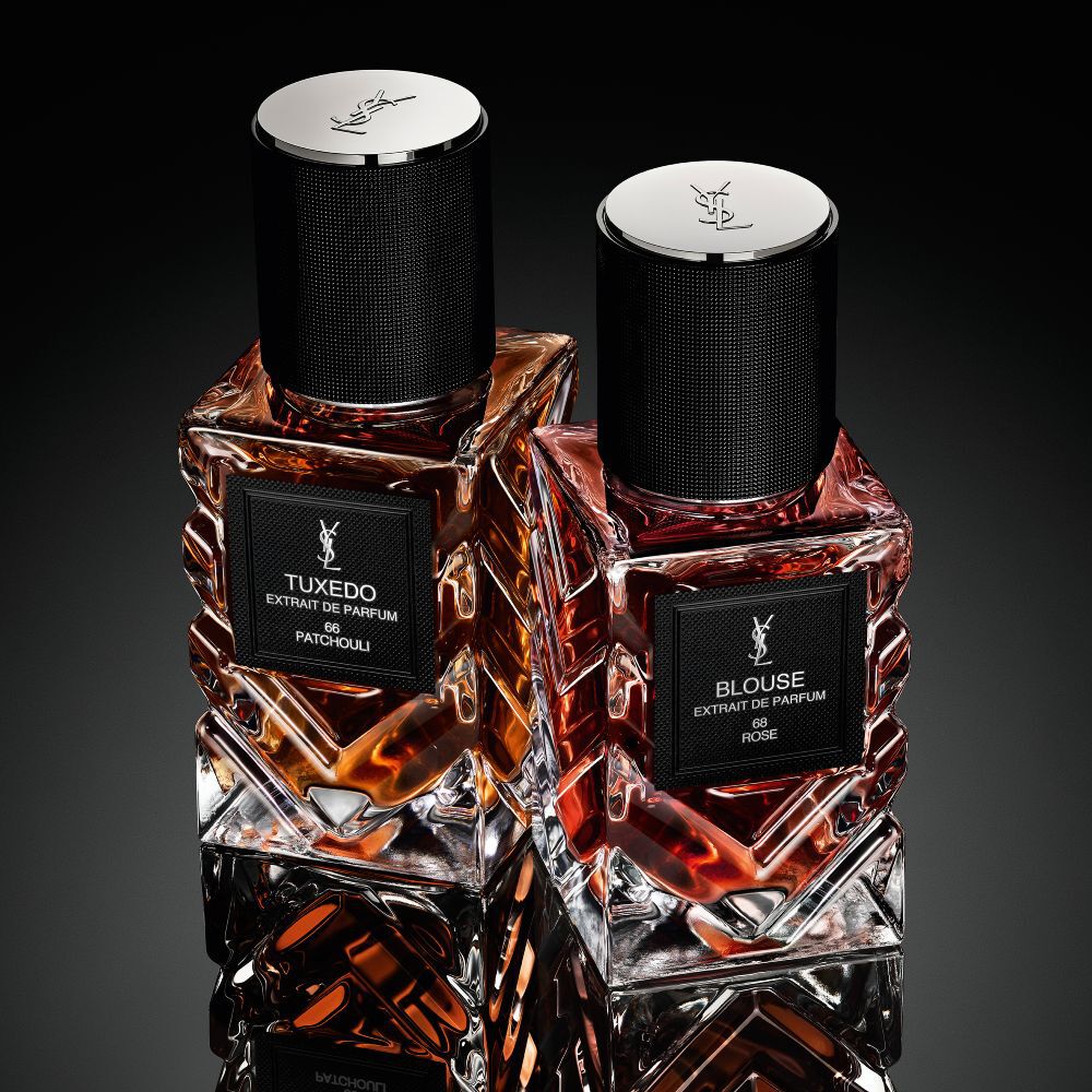 Una collezione di flaconi della linea "Le Vestiaire des Parfums" di Yves Saint Laurent disposti a forma di diamante su una superficie nera riflettente.