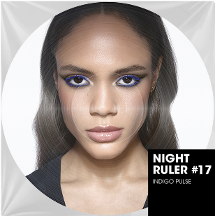 Un ritratto ravvicinato a colori di una donna dai capelli lunghi e lisci e dalla carnagione chiara. I suoi occhi sono intensamente truccati con un eyeliner blu elettrico vibrante e un ombretto bronzo. Le sue labbra sono naturali e lucide. In basso a destra dell'immagine circolare, un'incrustazione rettangolare nera indica "NIGHT RULER #17" e "INDIGO PULSE", suggerendo una collezione o un'atmosfera energica e audace, come il titolo di un brano musicale.