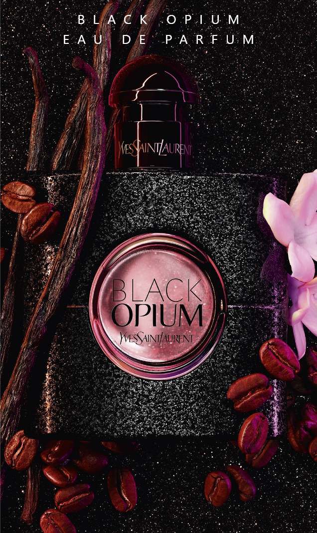 Profumo Black Opium di Yves Saint Laurent, circondato da chicchi di caffe, vaniglia e un fiore, su uno sfondo scuro.