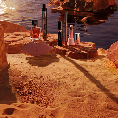 Trucco, profumi YSL e pochette bianca in un deserto soleggiato.