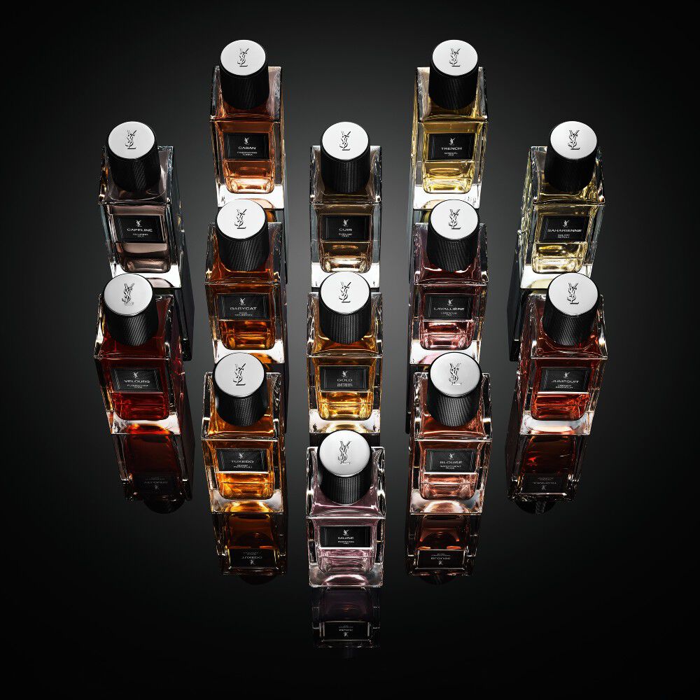 Una collezione di flaconi della linea "Le Vestiaire des Parfums" di Yves Saint Laurent disposti a forma di diamante su una superficie nera riflettente.