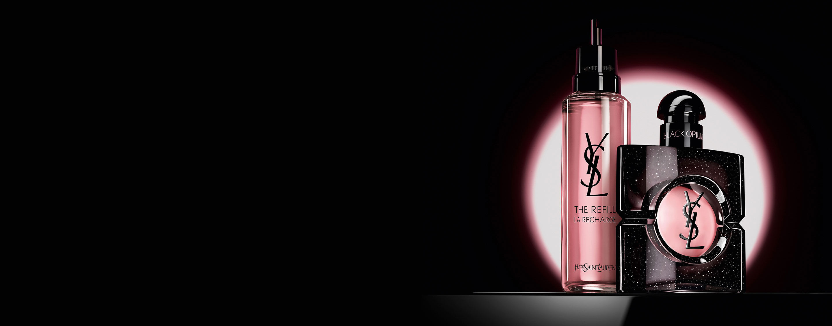Il flacone Black Opium Eau de Parfum accanto al suo flacone di ricarica in vetro da 100 ml con il logo YSL.