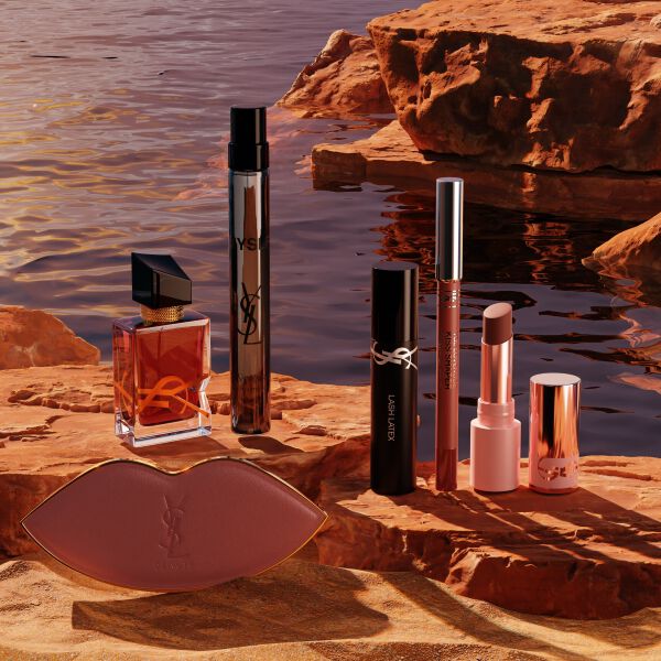 Trucco, profumi YSL e pochette bianca in un deserto soleggiato.