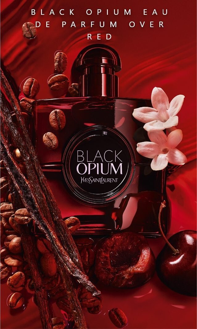 Un profumo Black Opium di Yves Saint Laurent, circondato da chicchi di caffe, rami di vaniglia e fiori su uno sfondo rosso.