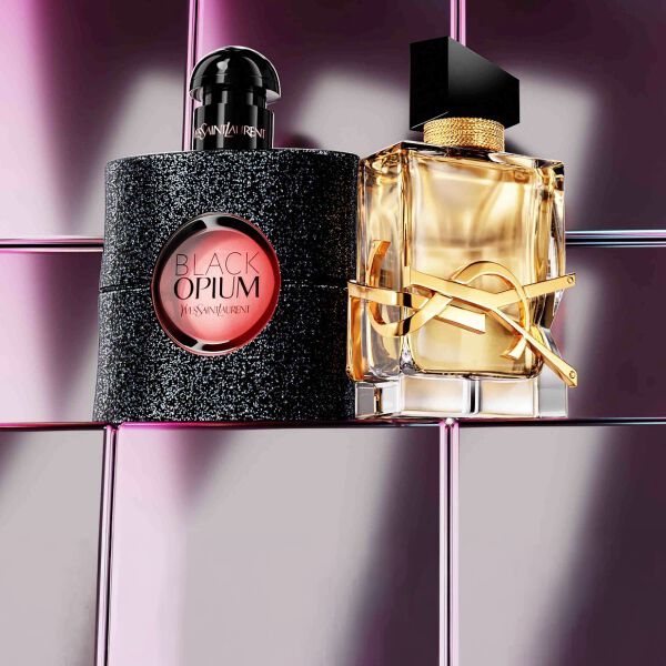 Prodotti di bellezza YSL tra cui una trousse trapuntata, un mascara e due rossetti su sfondo in piastrelle rosa lucide.