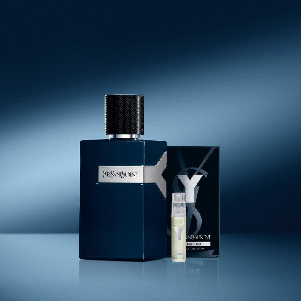 A stylish blue perfume bottle from Yves Saint Laurent alongside a small travel-sized spray and packaging, set against a gradient blue background.
