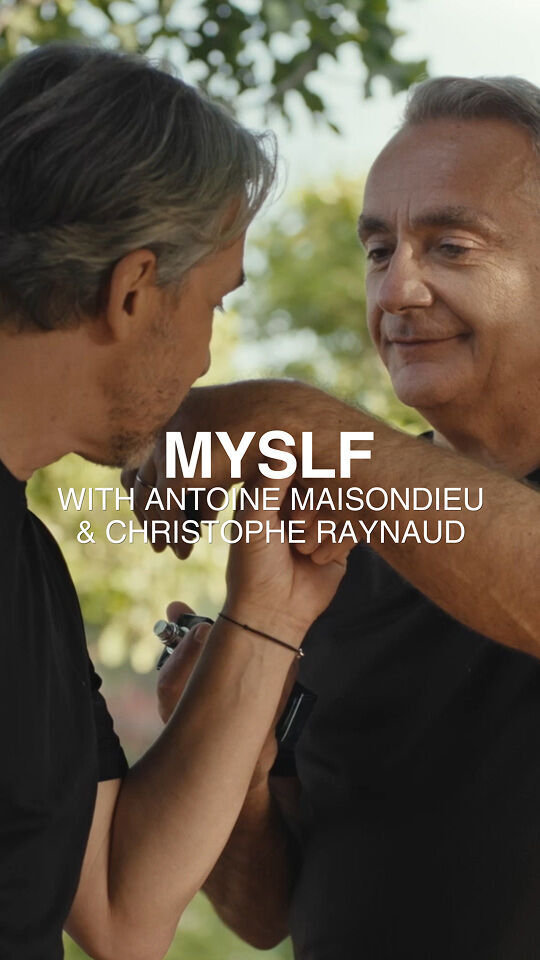 Due uomini in maglietta nera interagiscono all'aperto, con uno che tiene il braccio dell'altro e un piccolo oggetto. All'immagine si sovrappone il testo "MYSLF WITH ANTOINE MAISONDIEU & CHRISTOPHE RAYNAUD" su uno sfondo sfocato di fogliame verde.