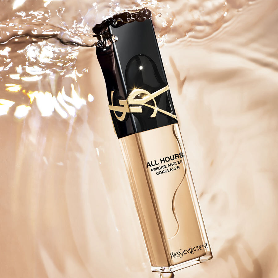 A bottle of Yves Saint Laurent All Hours Precise Anoles Concealer with a sleek black and gold design, partially submerged in liquid.