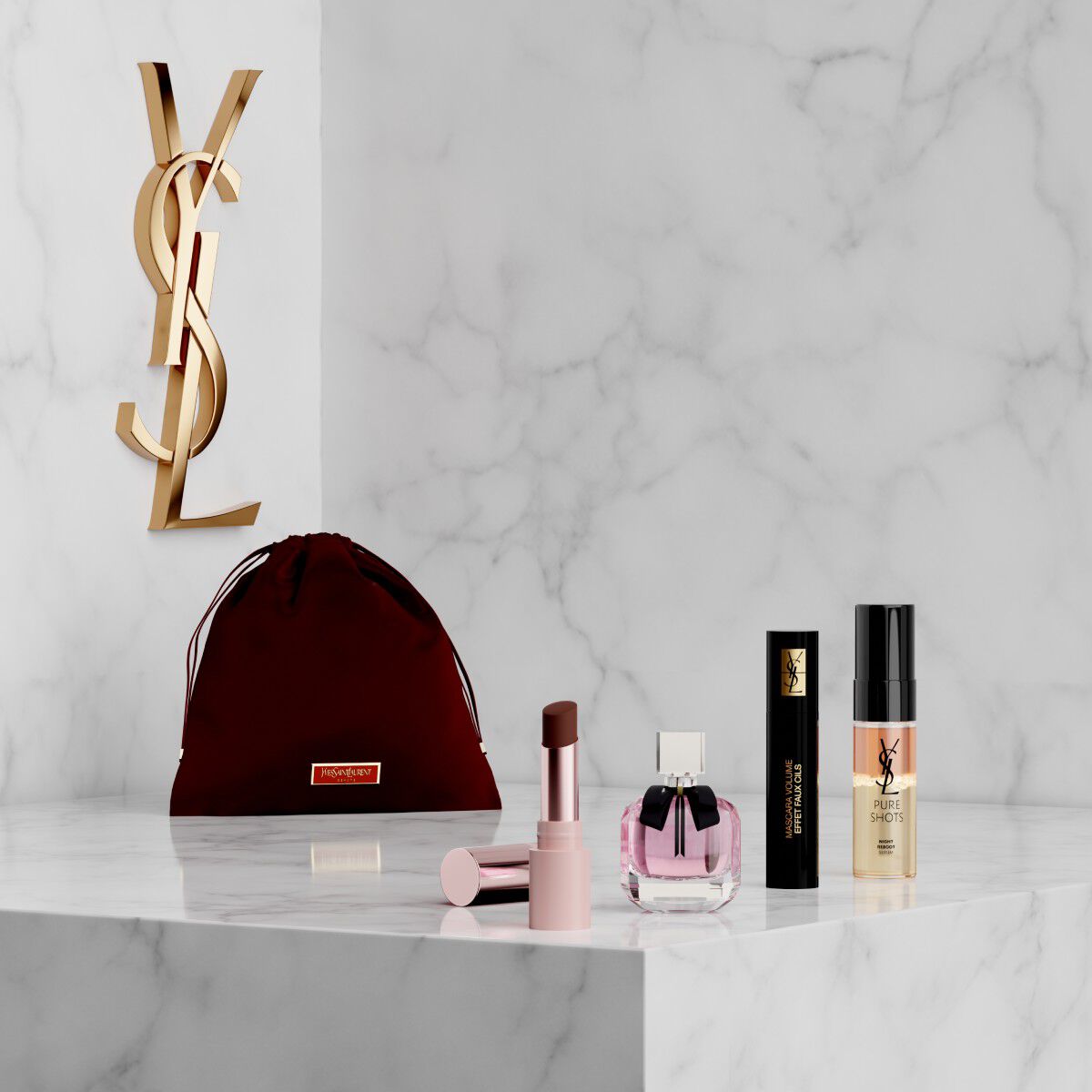 Set YSL Beauty con pochette rosa, rossetto, eyeliner, mascara e mini profumo su mensola in marmo.