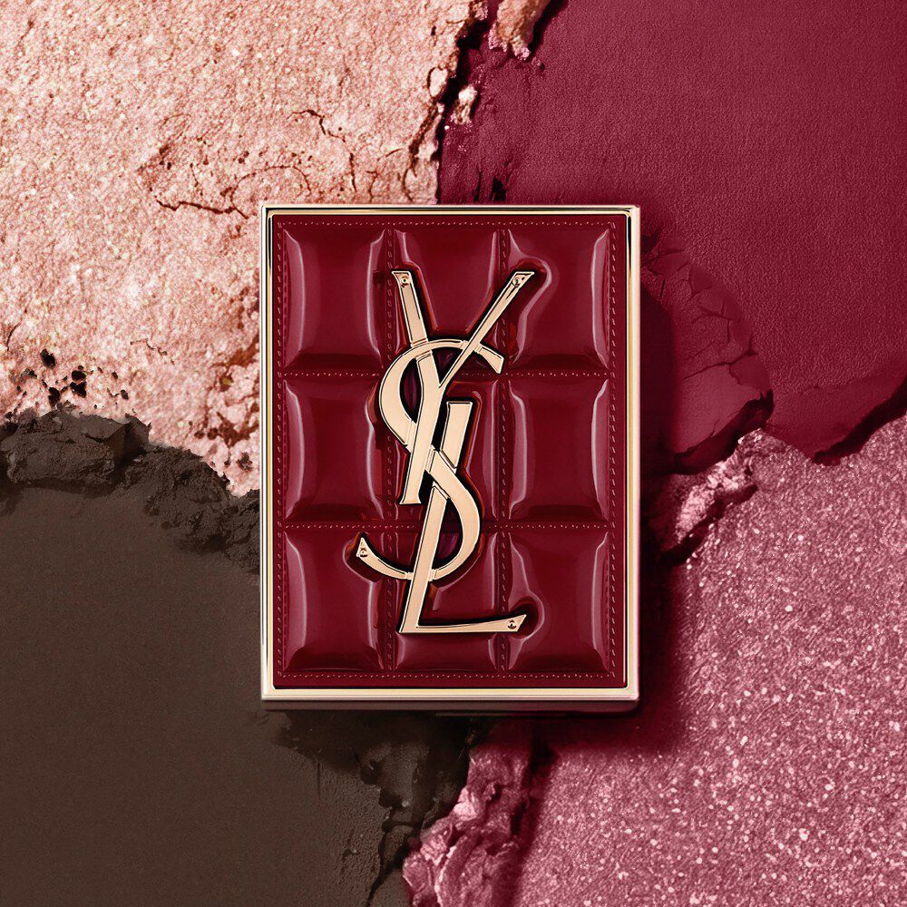 YSL Couture Mini Clutch si staglia su uno sfondo testurizzato di ombretti scintillanti, polvere di #1982 Burgundy Millesime.