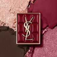 YSL Couture Mini Clutch si staglia su uno sfondo testurizzato di ombretti scintillanti, polvere di #1982 Burgundy Millesime.