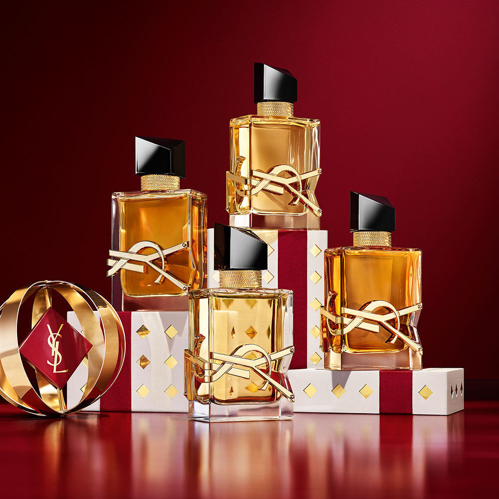 Flaconi di YSL LIBRE sovrapposti su confezioni regalo Holiday dal pattern dorato di lusso.