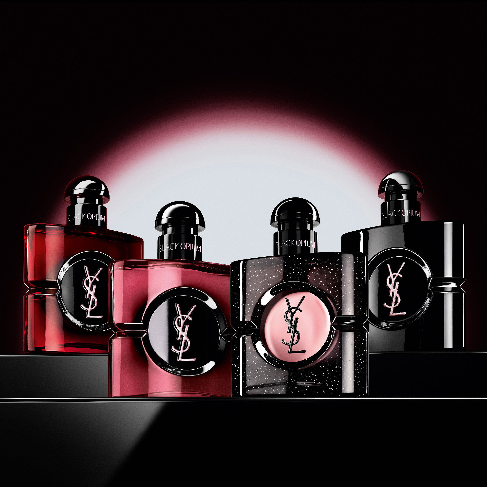 Quattro diversi flaconi di profumo Black Opium disposti in
                        fila su una superficie scura e riflettente.