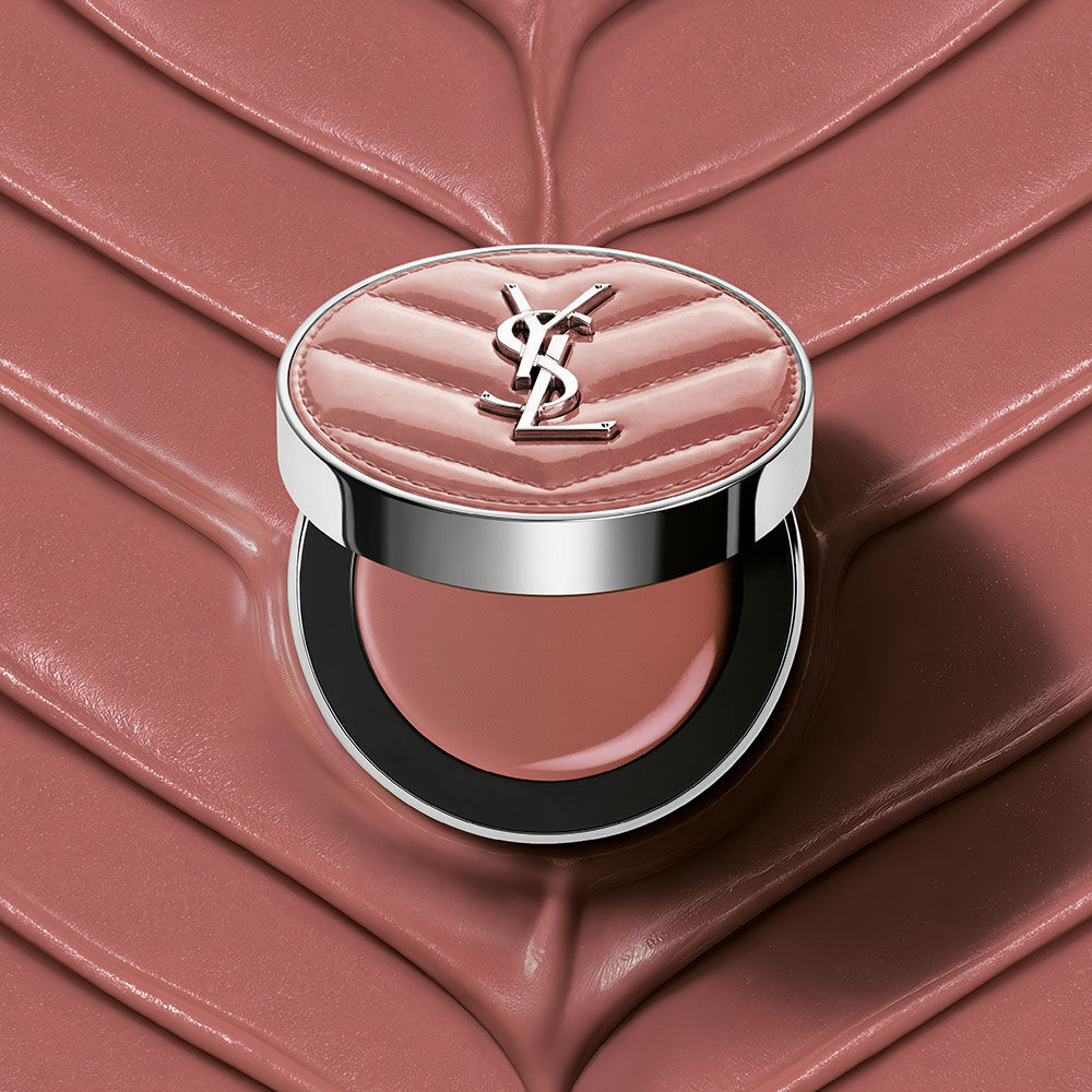 Un astuccio aperto di YSL Make Me Blush Lifted Glow Cream Blush nella tonalita #44 Nude Lavalliere su uno sfondo crema testurizzato rosa abbinato.
