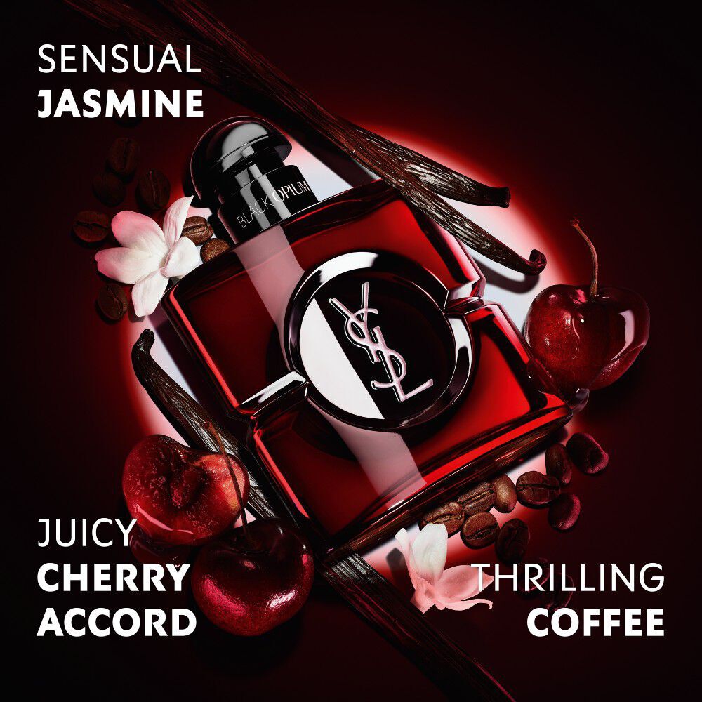 Flacone Black Opium Over Red in lacca rosso intenso, circondato da ciliegie rosse fresche e chicchi di caffe, con claim.
