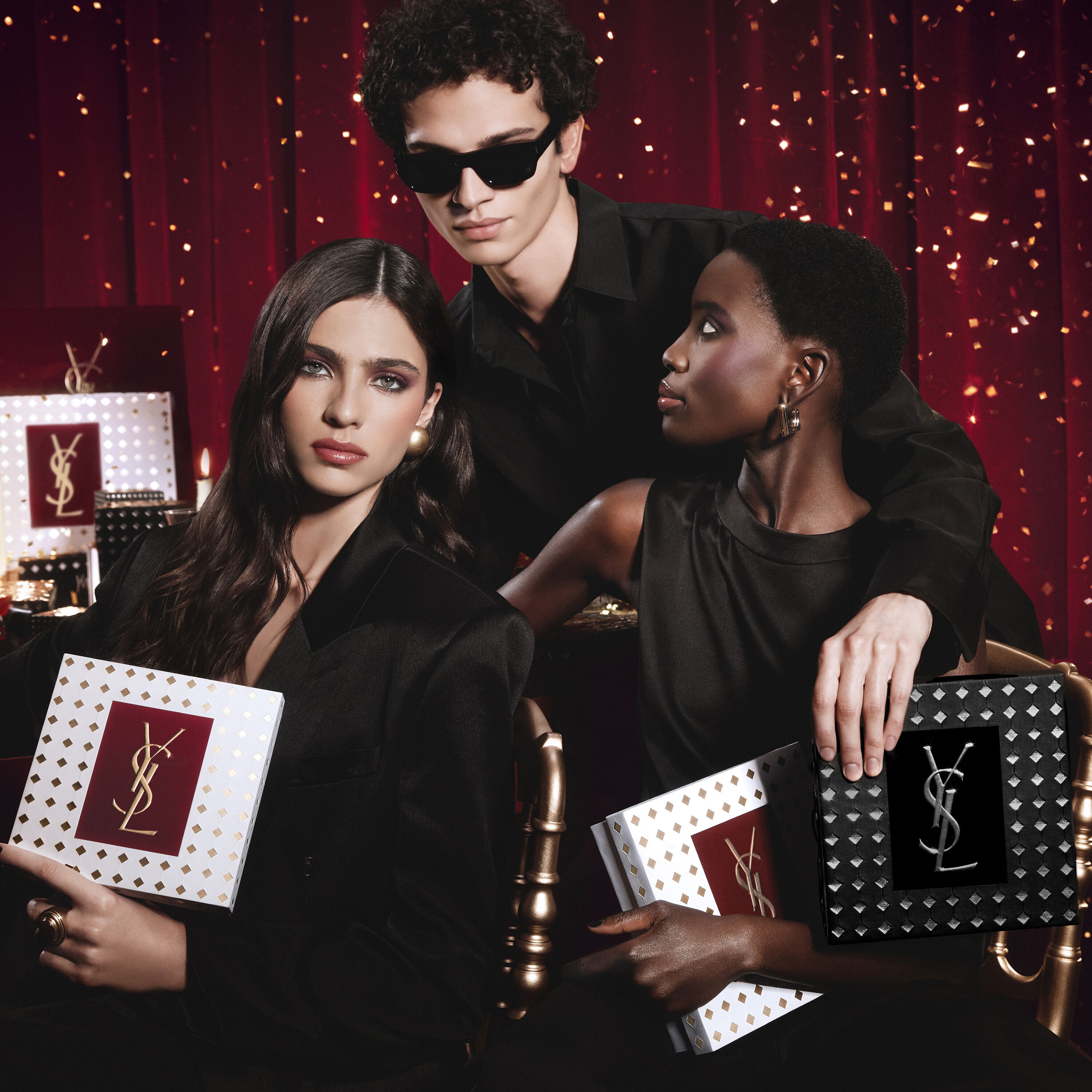 Modelle che posano insieme, reggendo lussuosi cofanetti regalo YSL Holiday in un’atmosfera festiva.