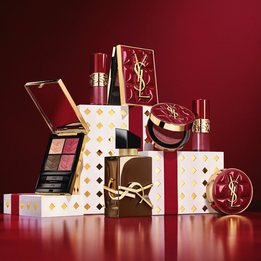 Collezione makeup YSL Holiday 2026 e set fragranza su piedistalli bianchi punteggiati d’oro, in un bagno di borgogna.