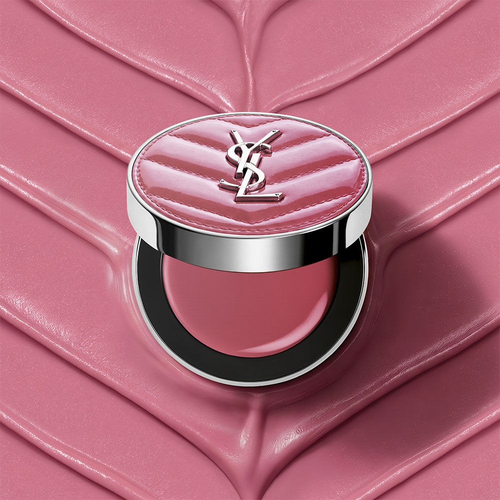 Un astuccio aperto di YSL Make Me Blush Lifted Glow Cream Blush nella tonalita #44 Nude Lavalliere su uno sfondo crema testurizzato rosa abbinato.