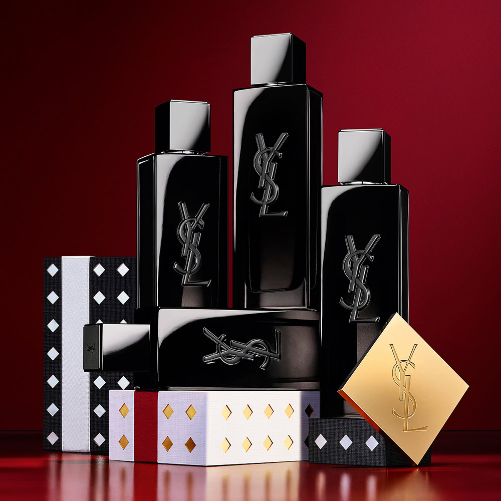 Flaconi di YSL MYSLF Eau de Parfum impilati su cofanetti regalo festivi con motivi neri e argentati.