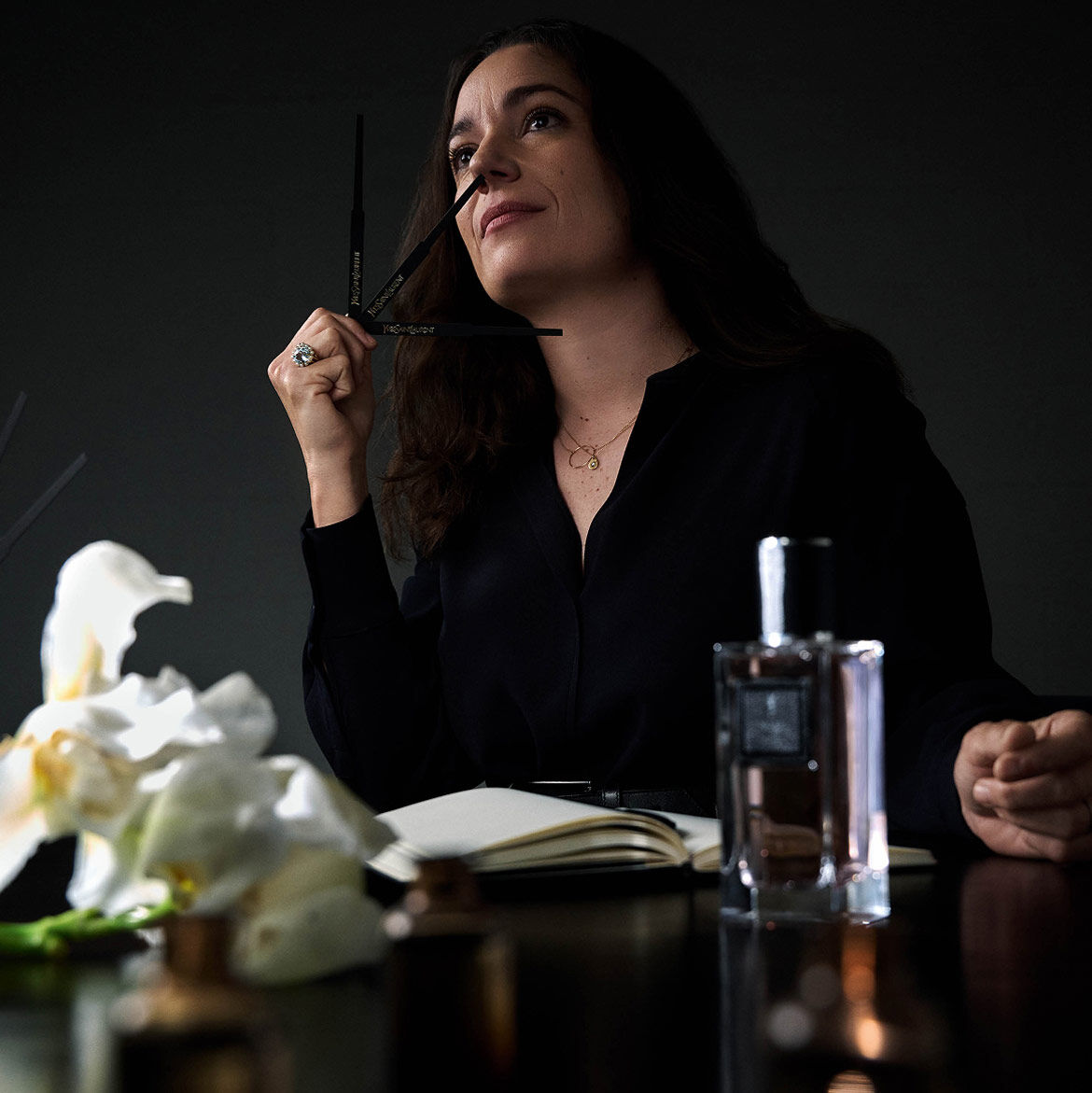 Donna che annusa mouillettes da profumo, con un taccuino e un flacone di profumo.