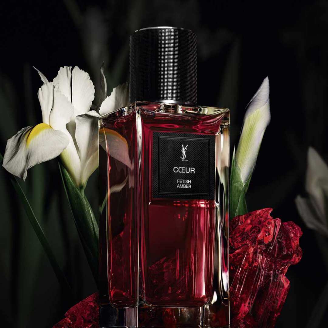 Flacone di profumo YSL rosso con fiori bianchi.
