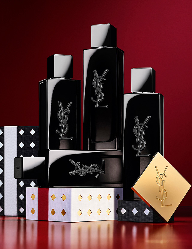 Flaconi di YSL MYSLF Eau de Parfum impilati su cofanetti regalo festivi con motivi neri e argentati.