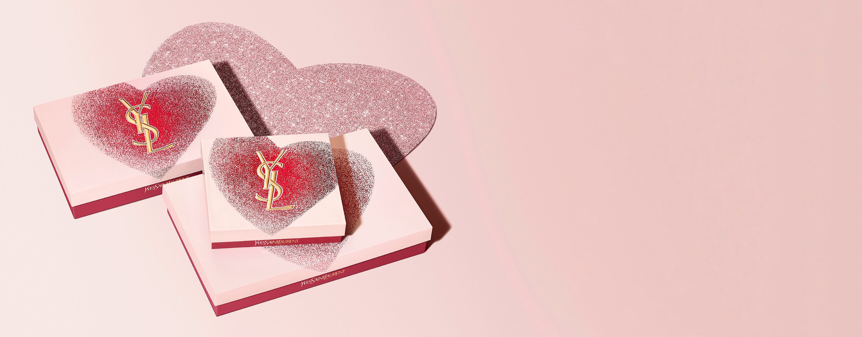 Set regalo per San Valentino YSL Beauty in scatole a forma di cuore con logo YSL dorato, caratterizzati da un design rosso e rosa glitterato.