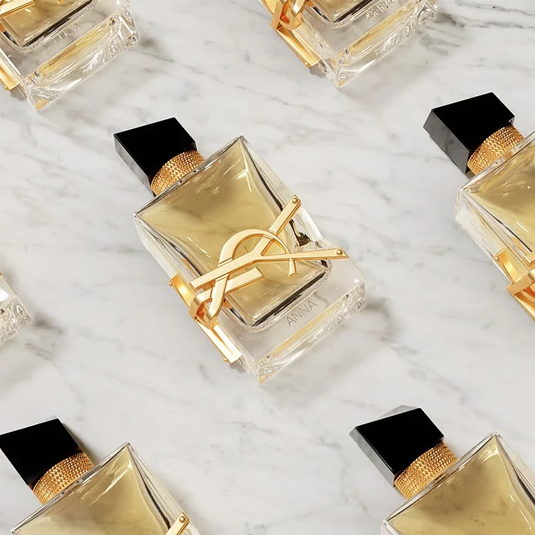 Flaconi di profumo YSL Libre personalizzati con incisioni di nomi, disposti su marmo bianco.