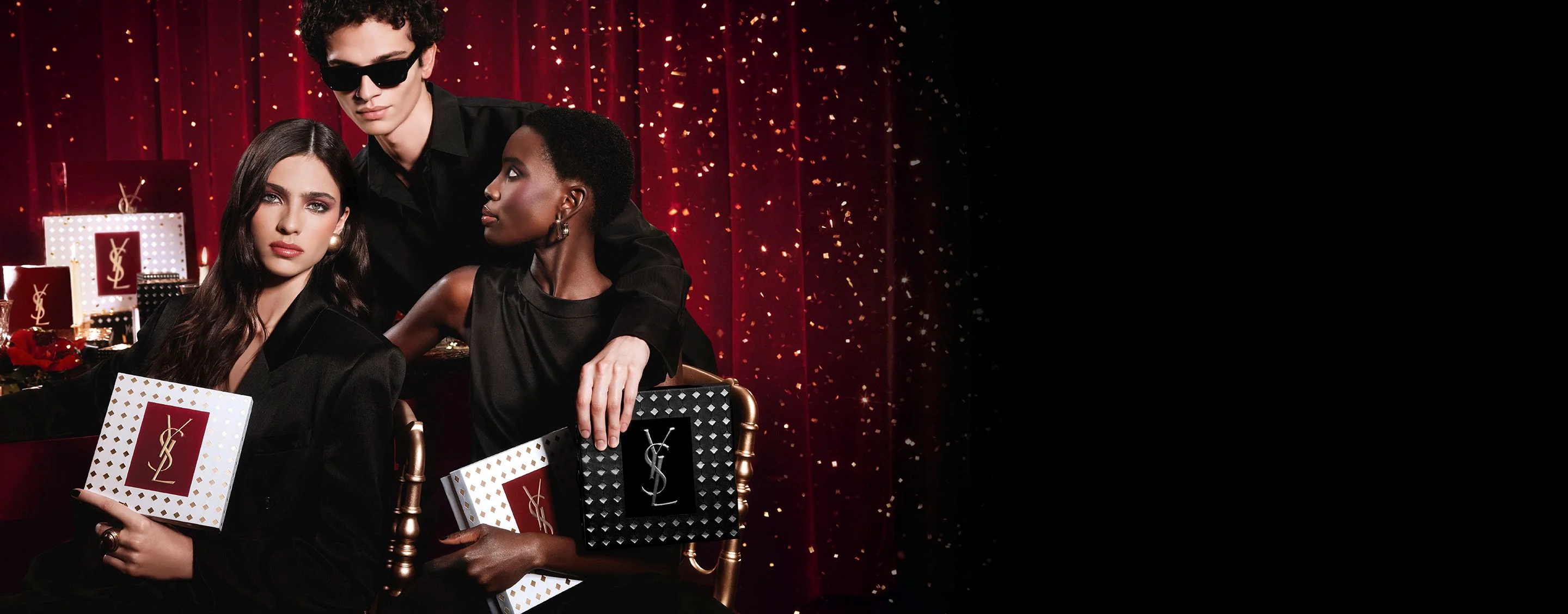 Models posing together holding luxury YSL Holiday gift boxes in a festive atmosphere.