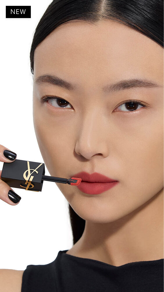 Modella asiatica con tono di pelle chiaro, applica una tonalità rosso-caldo di YSL THE INKS BLUR sulle labbra con l'applicatore a bacchetta.
